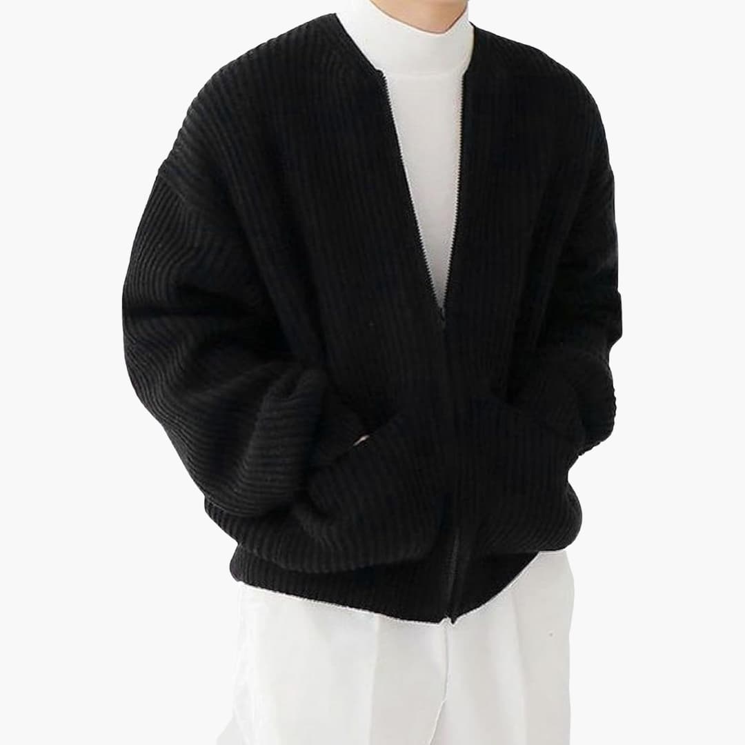 Veste cardigan noire en tricot côtelé, portée par une personne en pull blanc. Mode automne-hiver, style décontracté et élégant.