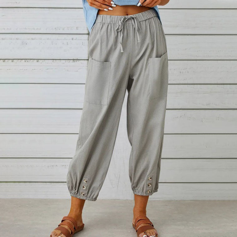 Pantalon ample gris pour femme avec poches avant, taille élastique et boutons décoratifs aux chevilles, style décontracté estival.