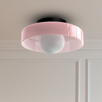 Plafonnier moderne rose avec abat-jour circulaire en verre, monté au plafond blanc. Éclairage intérieur design, luminaire tendance.