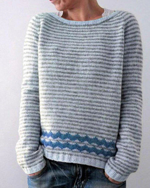 Pull rayé gris et bleu, manches longues, col rond, motif ondulé, porté par une personne. Mode décontractée, tendance automne-hiver.