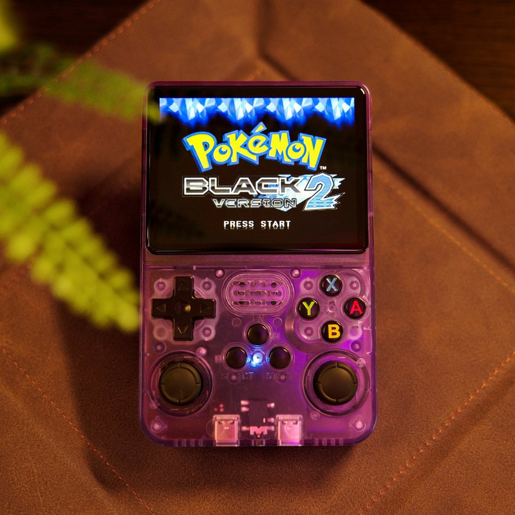 Console de jeu rétro violette avec écran affichant "Pokémon Black Version 2". Boutons colorés visibles. Fond en cuir marron.