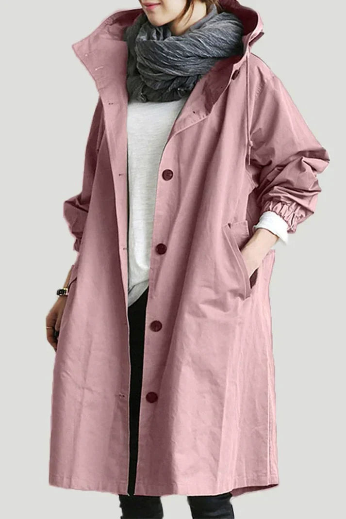 Femme portant un manteau rose ample avec boutons, écharpe grise, et chemise blanche. Mode automne, style décontracté, tendance féminine.
