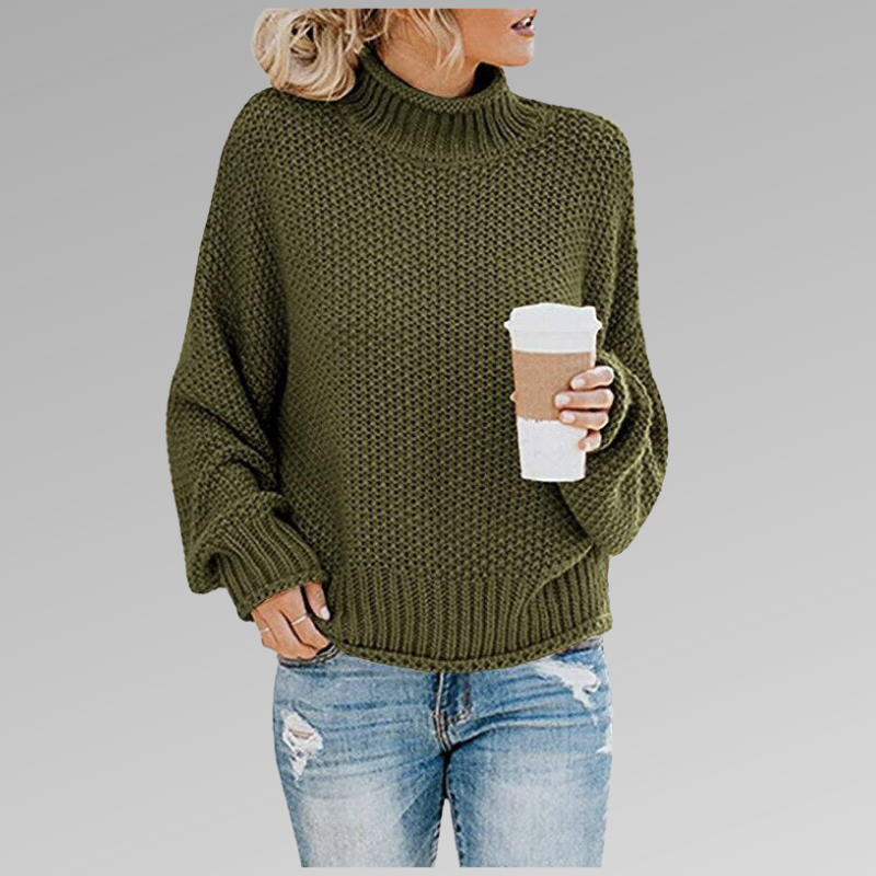 Femme en pull vert en maille avec col roulé, tenant un gobelet de café, portant un jean déchiré. Mode automne-hiver, style décontracté.