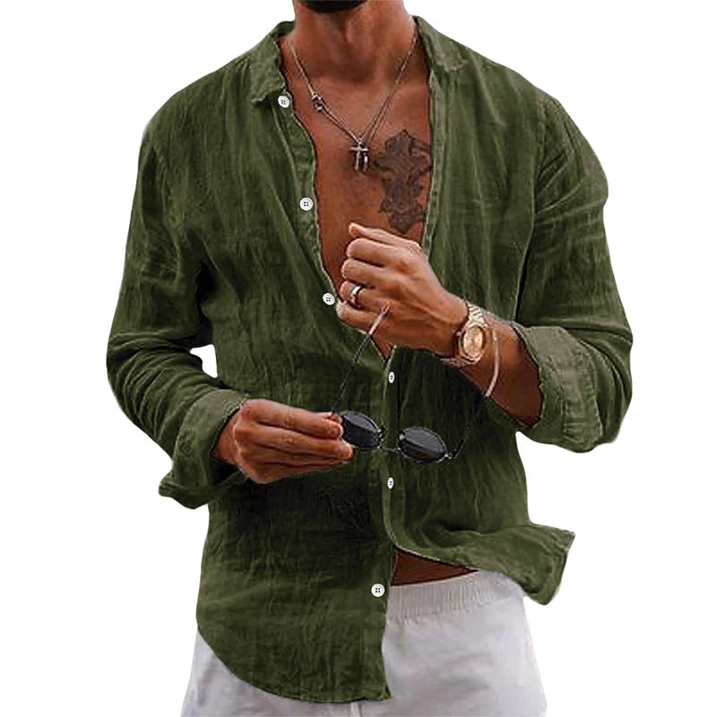 Homme portant une chemise en lin vert olive, ouverte, avec un collier et une montre dorée, tenant des lunettes de soleil noires. Mode décontractée élégante.
