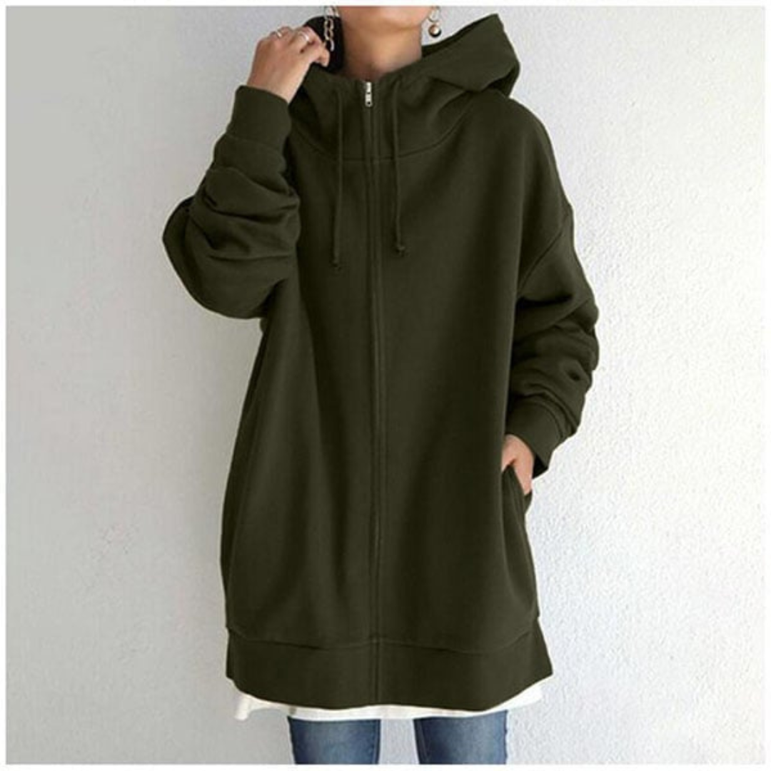 Veste à capuche oversize vert foncé pour femme, avec fermeture éclair, poches latérales, manches longues, portée sur un t-shirt blanc et un jean.