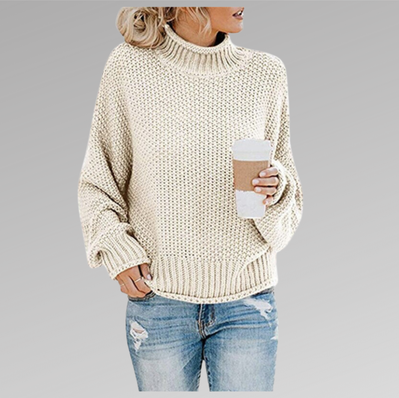 Femme portant un pull en tricot beige avec un col roulé, tenant un gobelet de café, vêtue d'un jean déchiré. Mode automne-hiver décontractée.