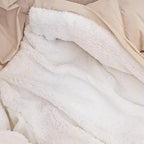 Veste en fausse fourrure blanche, douce et moelleuse, posée sur un fond beige. Mode hiver, confort, tendance, vêtement chaud.