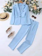 Costume bleu clair pour femme avec veste et pantalon, accompagné de chaussures beiges, chapeau de paille et lunettes de soleil, sur fond floral.