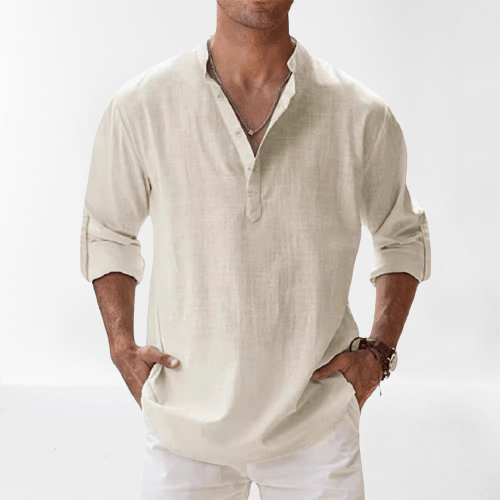 Homme portant une chemise en lin beige à manches longues retroussées, col tunisien, avec un collier et un bracelet, sur fond blanc.