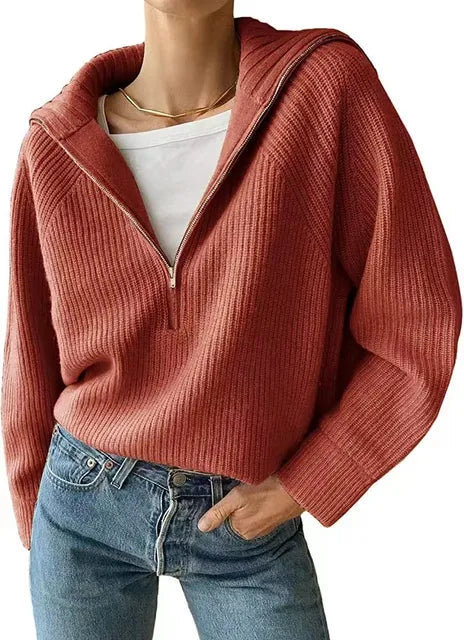 Femme portant un pull en maille côtelée rouge avec fermeture éclair, col large, sur un t-shirt blanc, associée à un jean bleu. Mode automne décontractée.