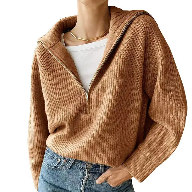 Femme portant un pull en maille marron à col zippé, superposé sur un t-shirt blanc, avec un jean bleu. Mode automne-hiver, style décontracté.
