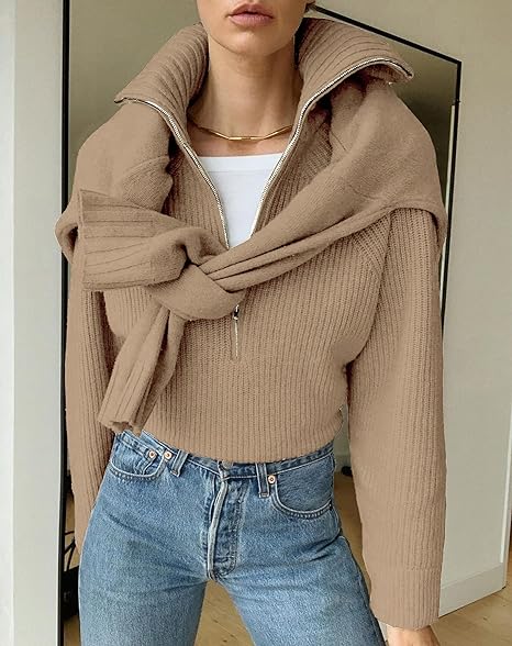 Femme portant un pull beige en maille avec un col zippé, noué autour des épaules, et un jean bleu. Mode automne, style décontracté chic.
