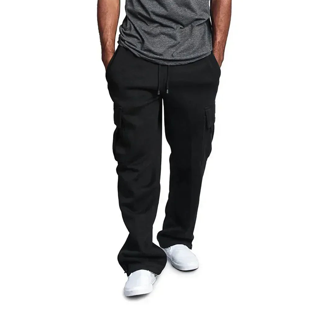 Pantalon cargo noir pour homme, style décontracté, avec poches latérales, cordon de serrage, porté avec t-shirt gris et baskets blanches.