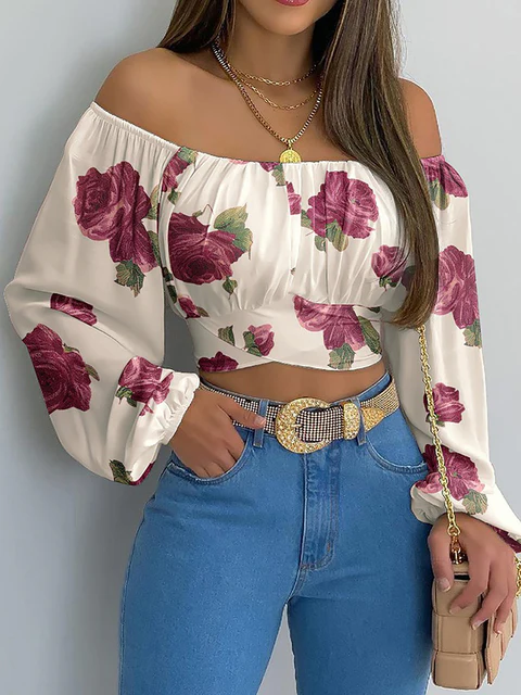 Femme portant un haut à épaules dénudées avec motif floral rose, jean bleu taille haute, ceinture dorée, et sac à main beige. Mode féminine élégante.