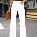 Femme portant un jean blanc évasé, tenant une pochette marron, debout sur un passage piéton. Mode urbaine, style décontracté, tendance 2023.