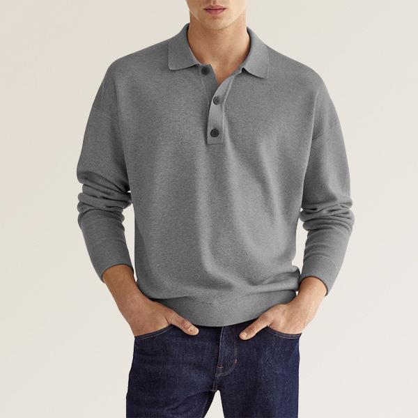 Homme portant un pull gris à col polo et manches longues, associé à un jean bleu foncé. Mode masculine élégante et décontractée.