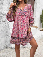 Robe bohème rose à motifs floraux, manches longues, portée par une femme. Style décontracté, idéal pour l'été. Fond blanc avec cactus.