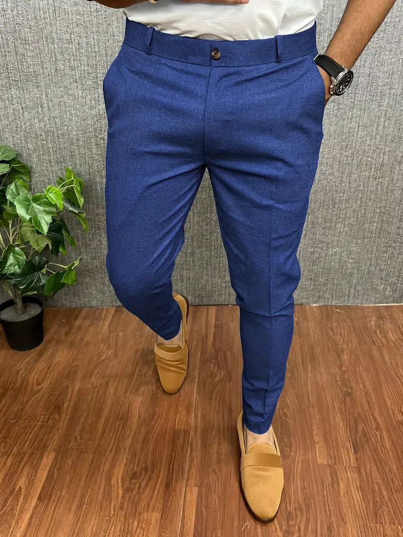 Pantalon bleu homme élégant, coupe ajustée, avec mocassins marron clair sur parquet. Mode masculine, tenue chic, style moderne.