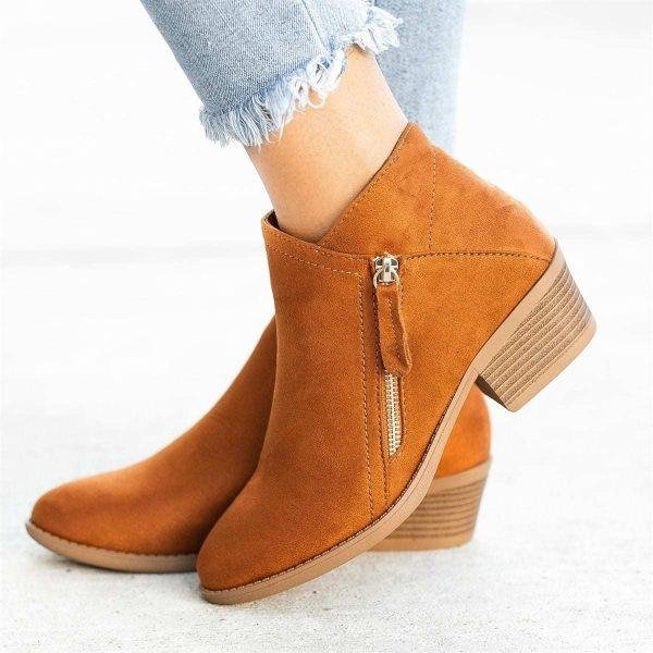 Bottines en daim marron avec talon bas, fermeture éclair latérale, portées avec un jean déchiré. Chaussures tendance automne-hiver pour femmes.