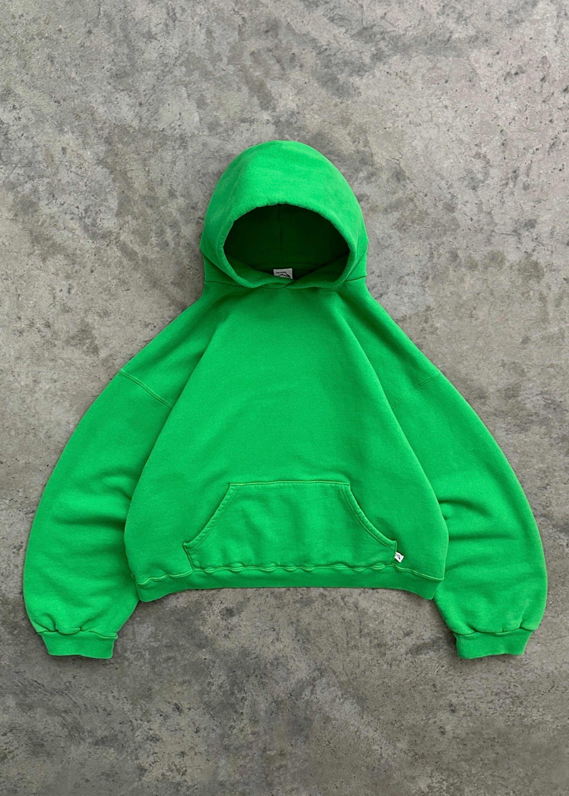 Sweat à capuche vert vif sur fond gris, style décontracté, poche kangourou, manches longues, mode urbaine, vêtement tendance, streetwear.