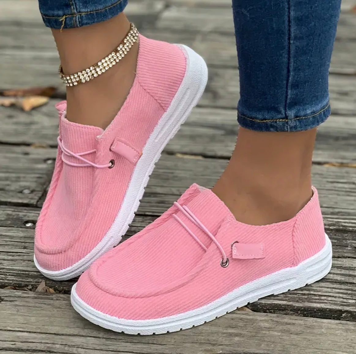 Chaussures roses en toile pour femme, style décontracté, avec semelle blanche, portées avec un jean. Accessoire: bracelet de cheville brillant.