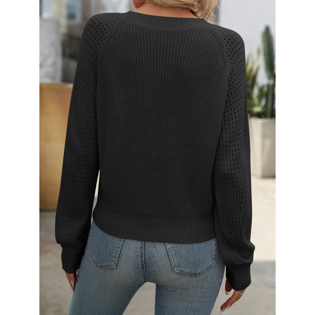 Femme portant un pull noir en maille ajourée, manches longues, vue de dos, avec un jean bleu, dans un cadre extérieur moderne.
