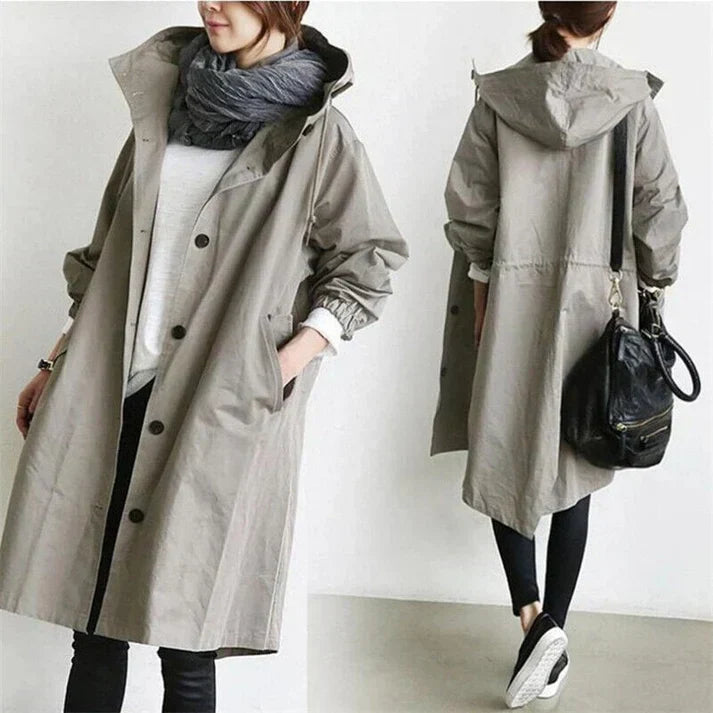 Femme portant un manteau trench beige avec capuche, écharpe grise, sac noir, tenue décontractée, mode automne-hiver, style urbain chic.