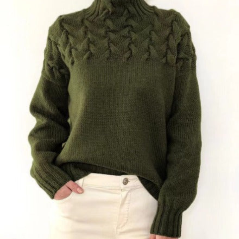 Pull en laine vert olive avec col roulé et motif torsadé, porté avec un pantalon beige. Mode automne-hiver, style décontracté et élégant.