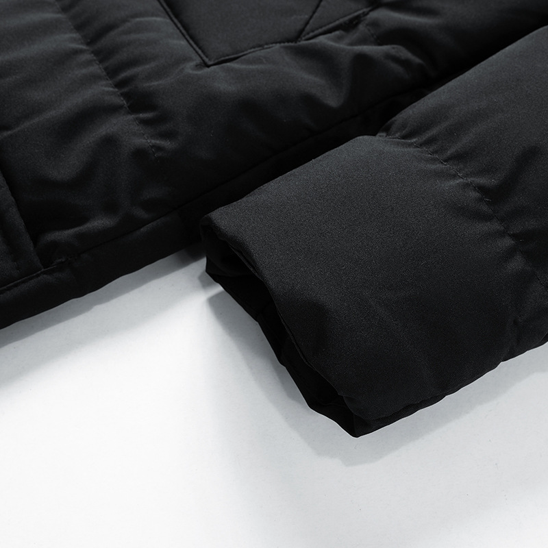 Manche de manteau noir matelassé, tissu épais et chaud, gros plan. Mode hiver, vêtement isolant, style moderne et élégant.