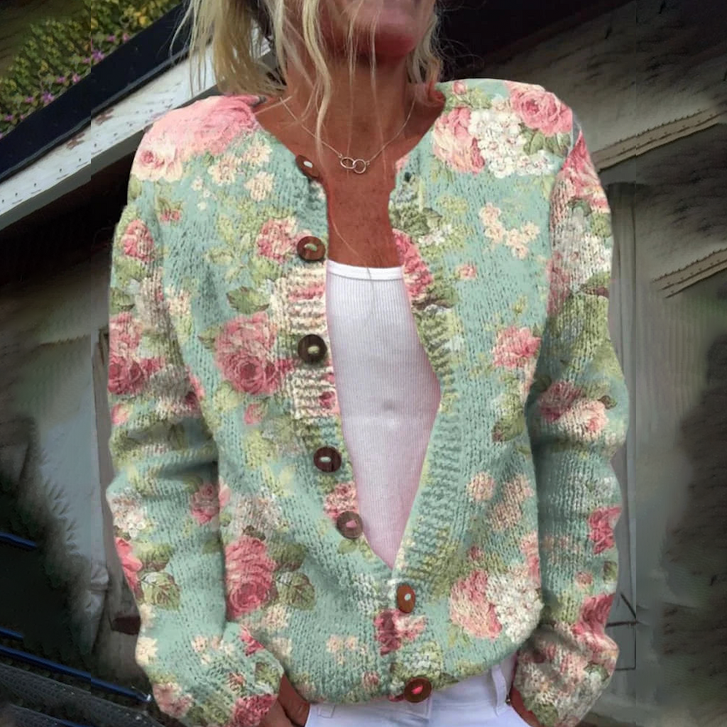 Femme portant un cardigan en tricot à motifs floraux roses et verts, boutons en bois, sur un débardeur blanc. Mode féminine, style vintage.
