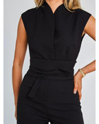 Combinaison noire élégante sans manches, ceinture nouée à la taille, portée par une femme. Mode chic, tenue de soirée, style moderne.