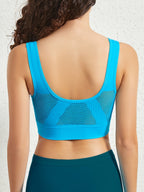 Femme de dos portant un débardeur de sport bleu avec empiècements en maille respirante, sur fond blanc. Mode fitness, vêtements de sport femme.