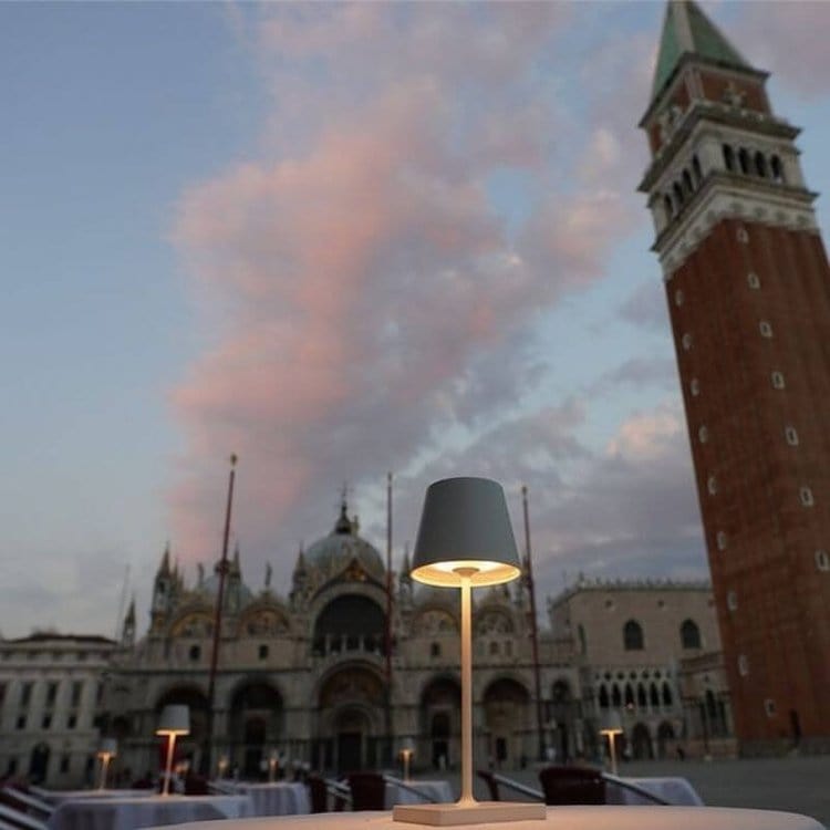 Lampe moderne sur table avec vue sur la Basilique Saint-Marc et le Campanile à Venise au crépuscule, ciel nuageux, ambiance romantique.