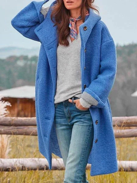 Femme portant un manteau bleu en laine, chemise grise et jean, posant en extérieur. Mode automne-hiver, style décontracté, tendance vestimentaire.