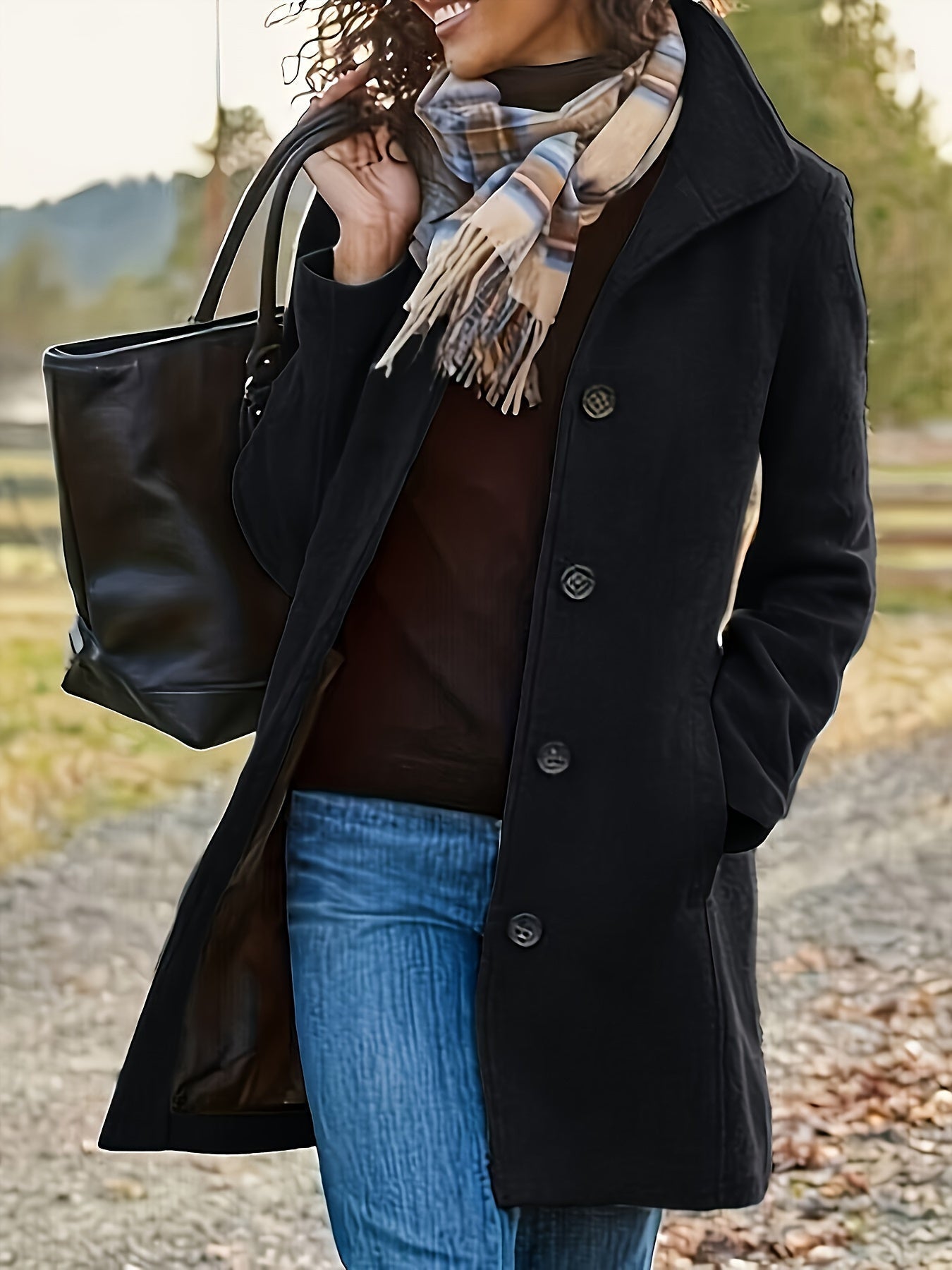 Femme portant un manteau noir élégant, écharpe à carreaux, sac à main en cuir noir, marchant en extérieur automnal. Mode hiver, style chic.