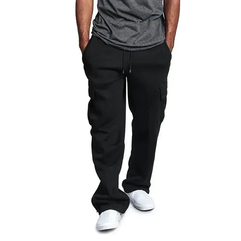 Pantalon cargo noir pour homme, style décontracté, avec poches latérales, cordon de serrage, porté avec t-shirt gris et baskets blanches.