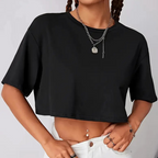 Femme portant un crop top noir, col rond, manches courtes, avec un collier en argent, posant en jean blanc. Mode tendance, style décontracté.