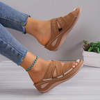 Sandales marron en cuir avec motifs ajourés, portées avec un jean bleu. Chaussures d'été confortables pour femmes, style décontracté et tendance.