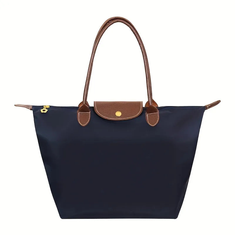 Sac à main en toile bleu marine avec poignées en cuir marron, design élégant et pratique, idéal pour le quotidien et les sorties.