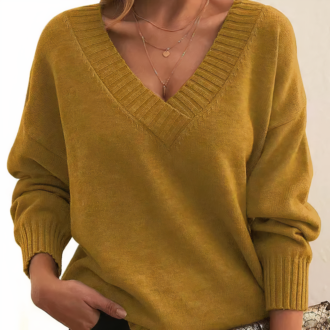 Femme portant un pull en maille jaune moutarde à col en V, manches longues, avec col côtelé. Mode automne, style décontracté et élégant.