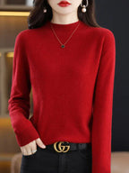 Femme portant un pull rouge élégant, collier délicat et ceinture noire avec boucle dorée. Mode automne-hiver, style chic et moderne.