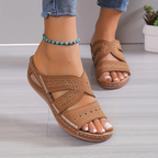 Sandales marron en cuir avec motifs ajourés, portées avec un bracelet de cheville turquoise. Mode estivale, chaussures confortables pour femmes.