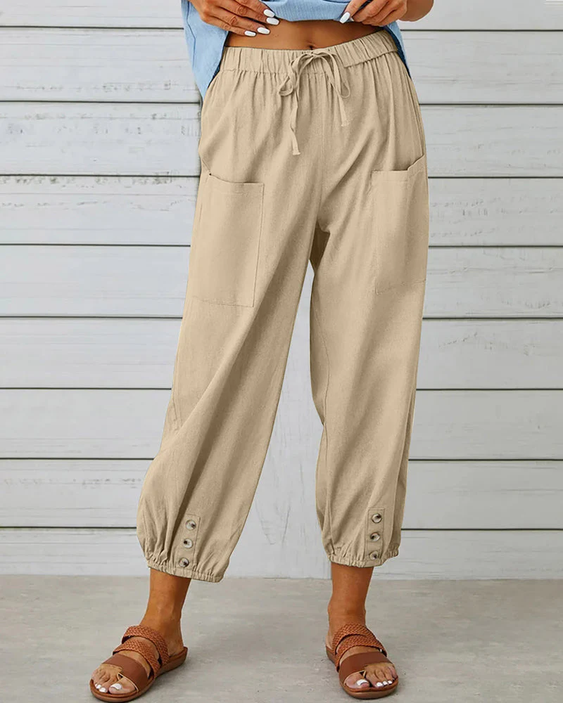 Pantalon beige ample en lin pour femme avec poches avant, taille élastique et boutons aux chevilles, idéal pour un look décontracté estival.