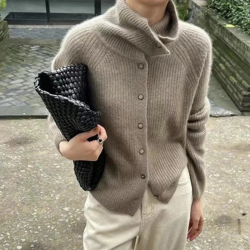 Femme portant un pull en laine beige avec un col roulé, tenant un sac à main tressé noir. Mode automne, style élégant et décontracté.