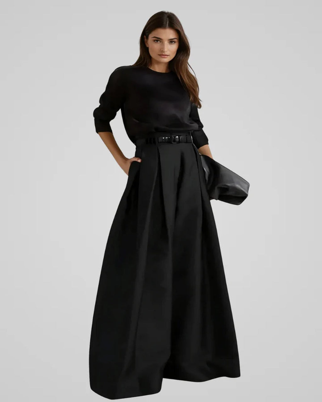 Femme portant une robe noire élégante avec manches longues et jupe ample, tenant une pochette. Mode chic, style minimaliste, tenue de soirée.