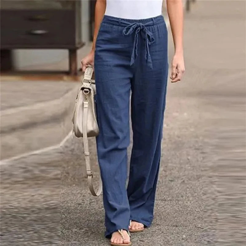 Pantalon large bleu en lin pour femme, avec cordon à la taille, porté avec un haut blanc. Mode décontractée, tendance estivale.