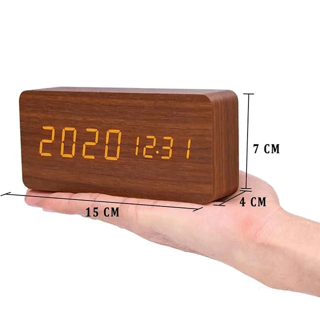 Horloge numérique en bois avec affichage LED orange, dimensions 15x7x4 cm, tenue dans une main. Design moderne, horloge de bureau élégante.