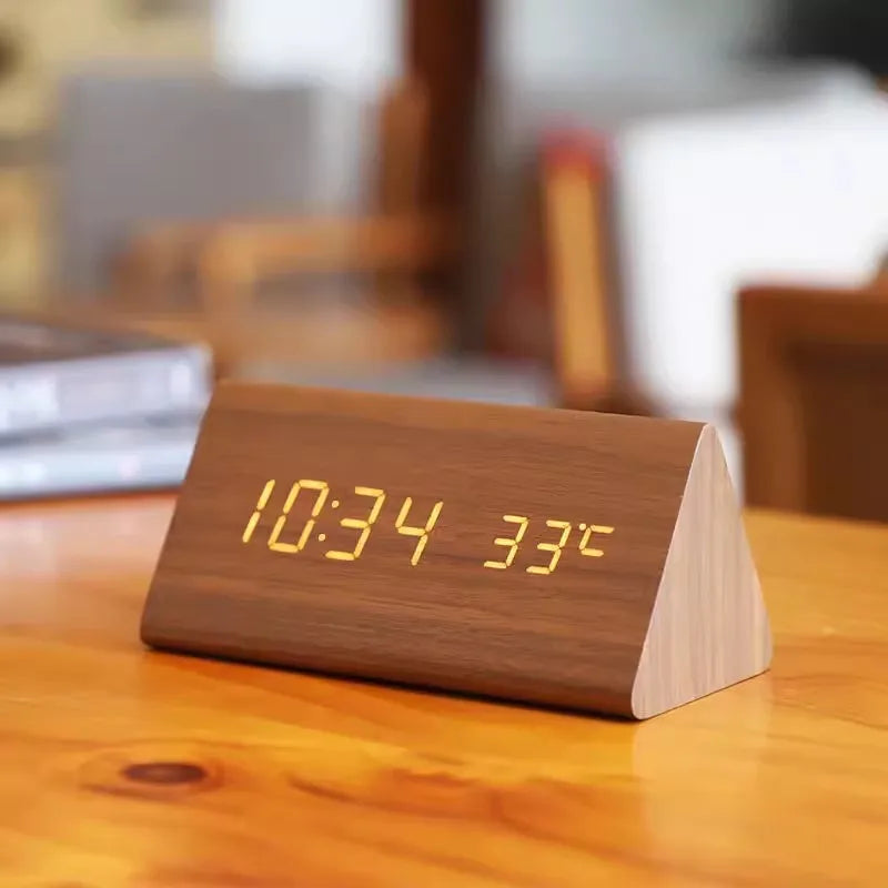 Horloge numérique en bois affichant l'heure 10:34 et la température 33°C, posée sur une table en bois, design moderne et minimaliste.