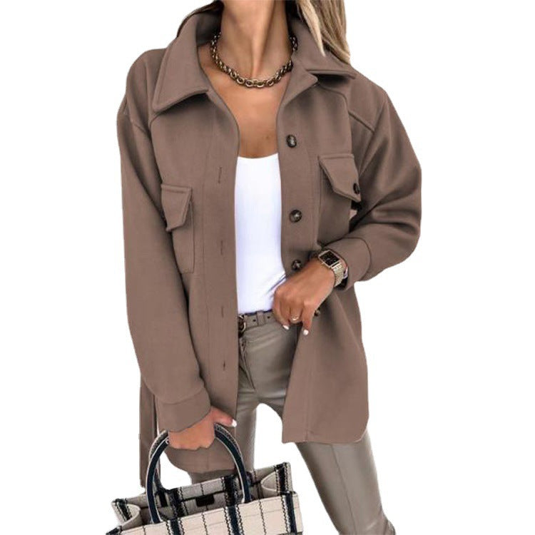 Femme portant une veste marron élégante avec boutons, chemise blanche, pantalon beige, collier doré, et sac à main à carreaux. Mode automne chic.
