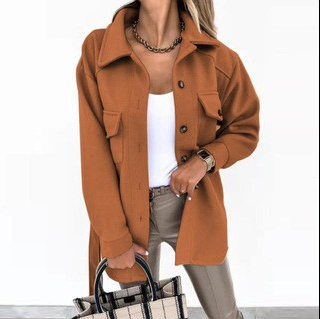 Femme portant une surchemise marron tendance, débardeur blanc, pantalon beige, tenant un sac à carreaux. Mode automne chic et moderne.